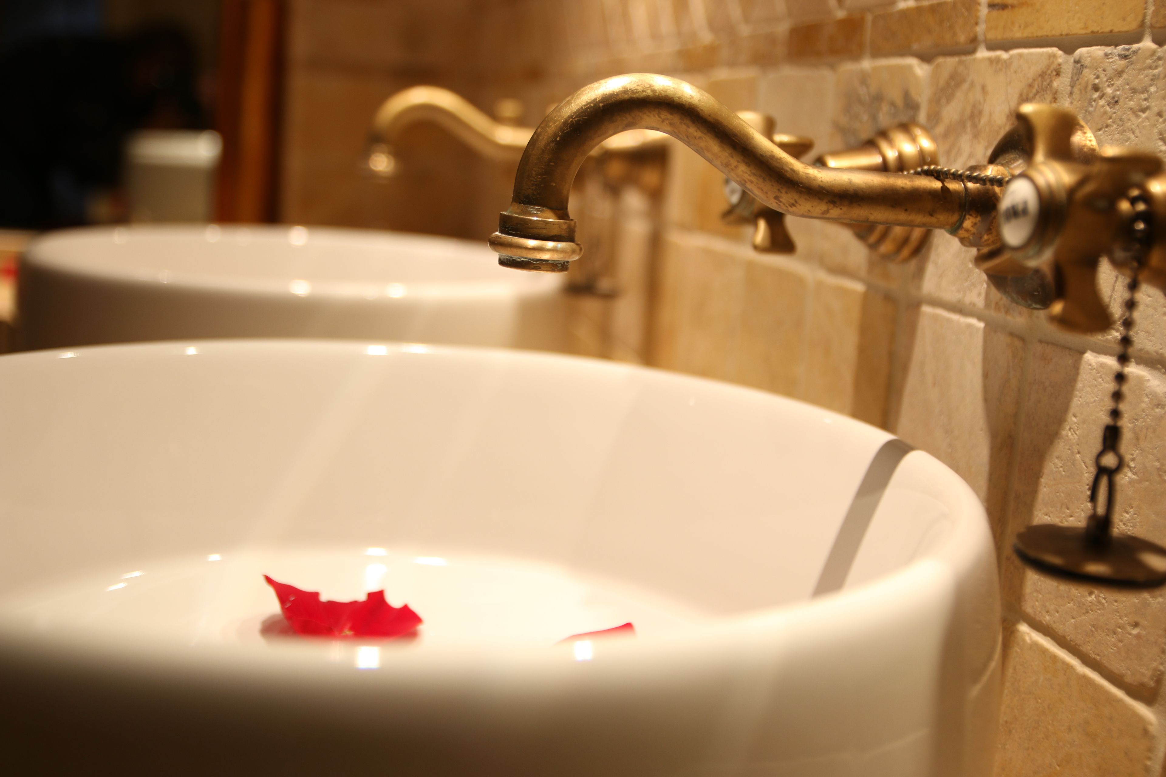 Un lavamanos con grifo de bronce y lavabo blanco.