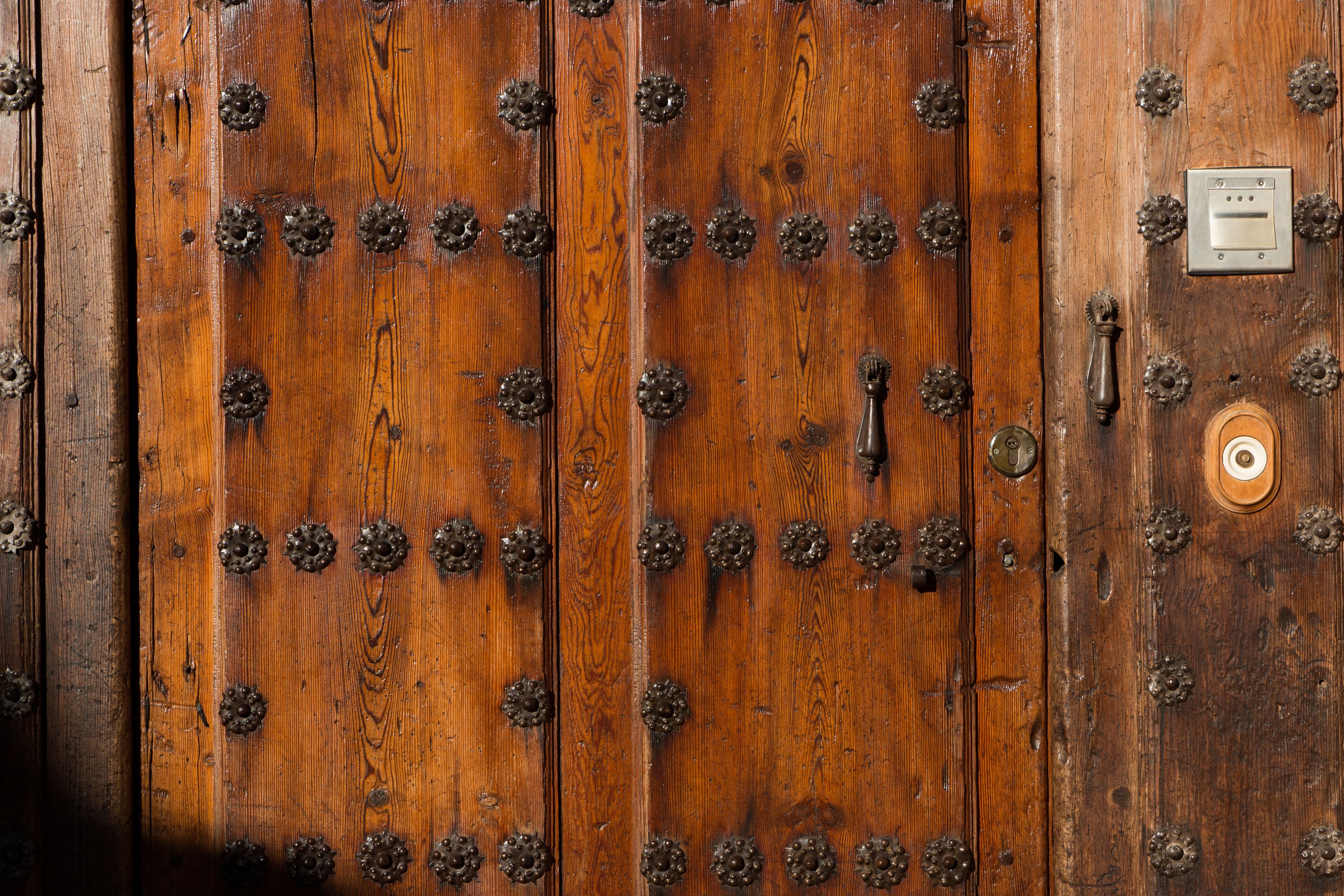 Une porte en bois, ornée de clous métalliques et dotée d’un mécanisme de verrouillage.