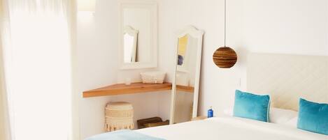 A bedroom with a bed, a nightstand, a mirror, and a hanging light fixture.