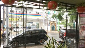A gas station with a black car parked in front, potted plants, and a metal gate. - Wisma Sentosa (Makassar)
