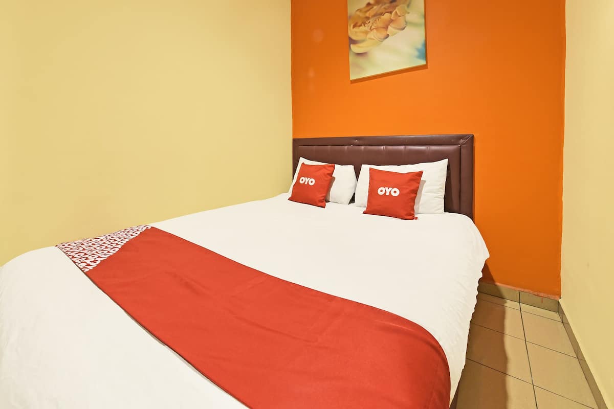 A hotel room with a bed, a headboard, and a wall painting.