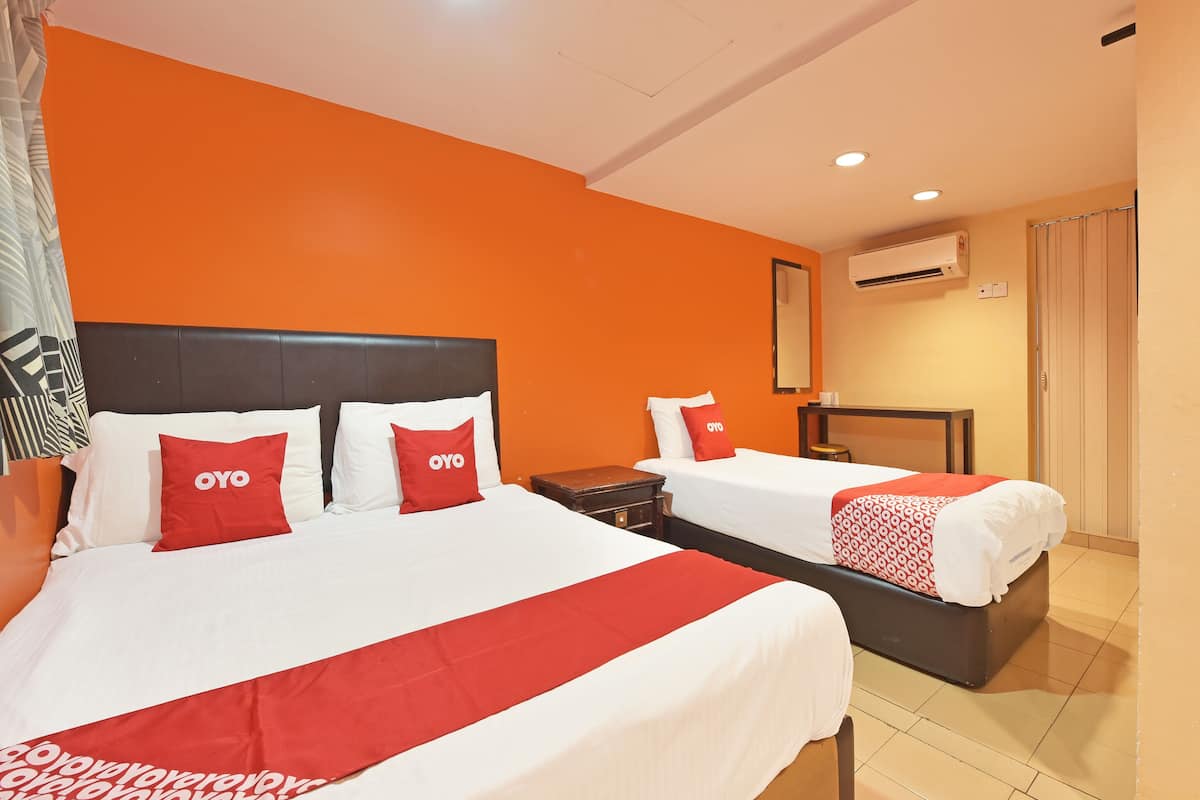 A hotel room with two beds, each with white and red bedding, and an orange accent wall.