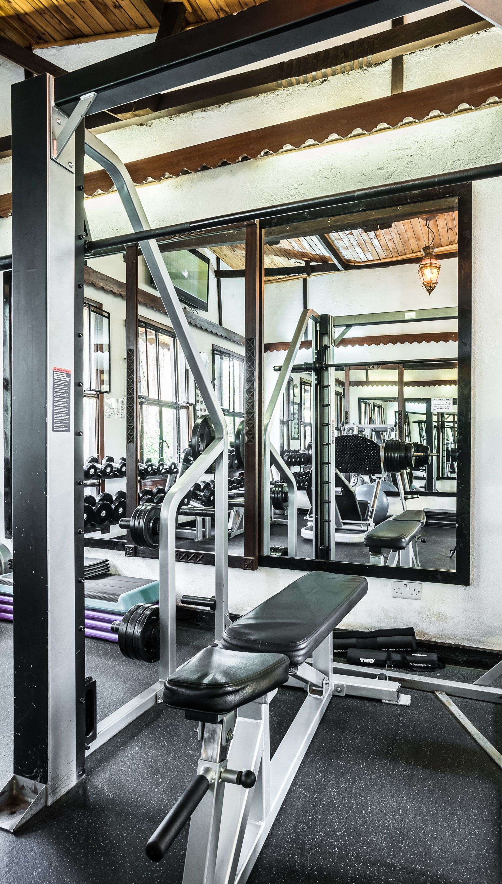 A gym with weightlifting equipment, benches, and dumbbells.