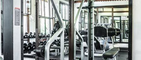 A gym with weightlifting equipment, benches, and dumbbells.
