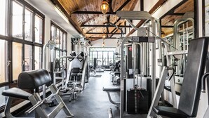 A gym with various exercise machines, large windows, and a wooden ceiling. - The King Post (Nairobi)