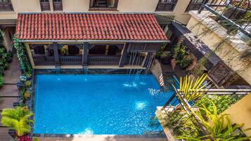 Een buitenzwembad, parasols bij het zwembad en ligstoelen