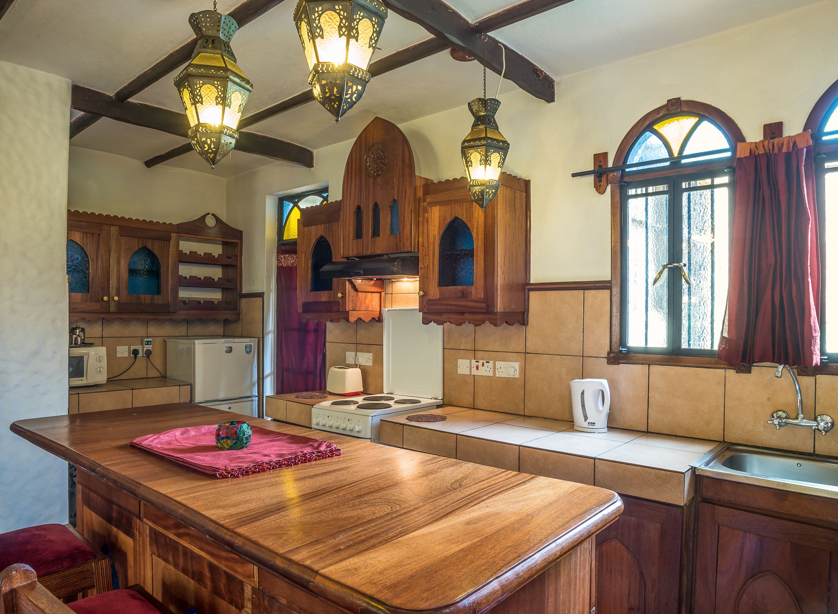 A kitchen with wooden cabinets, a central island, a sink, and a window with curtains.