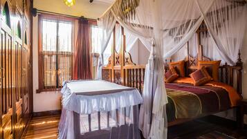 Une chambre traditionnelle avec un lit, une table et une fenêtre avec des rideaux.