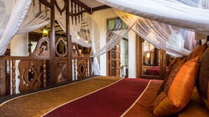 A room with a bed, wooden furniture, and a decorative partition. - The King Post (Nairobi)