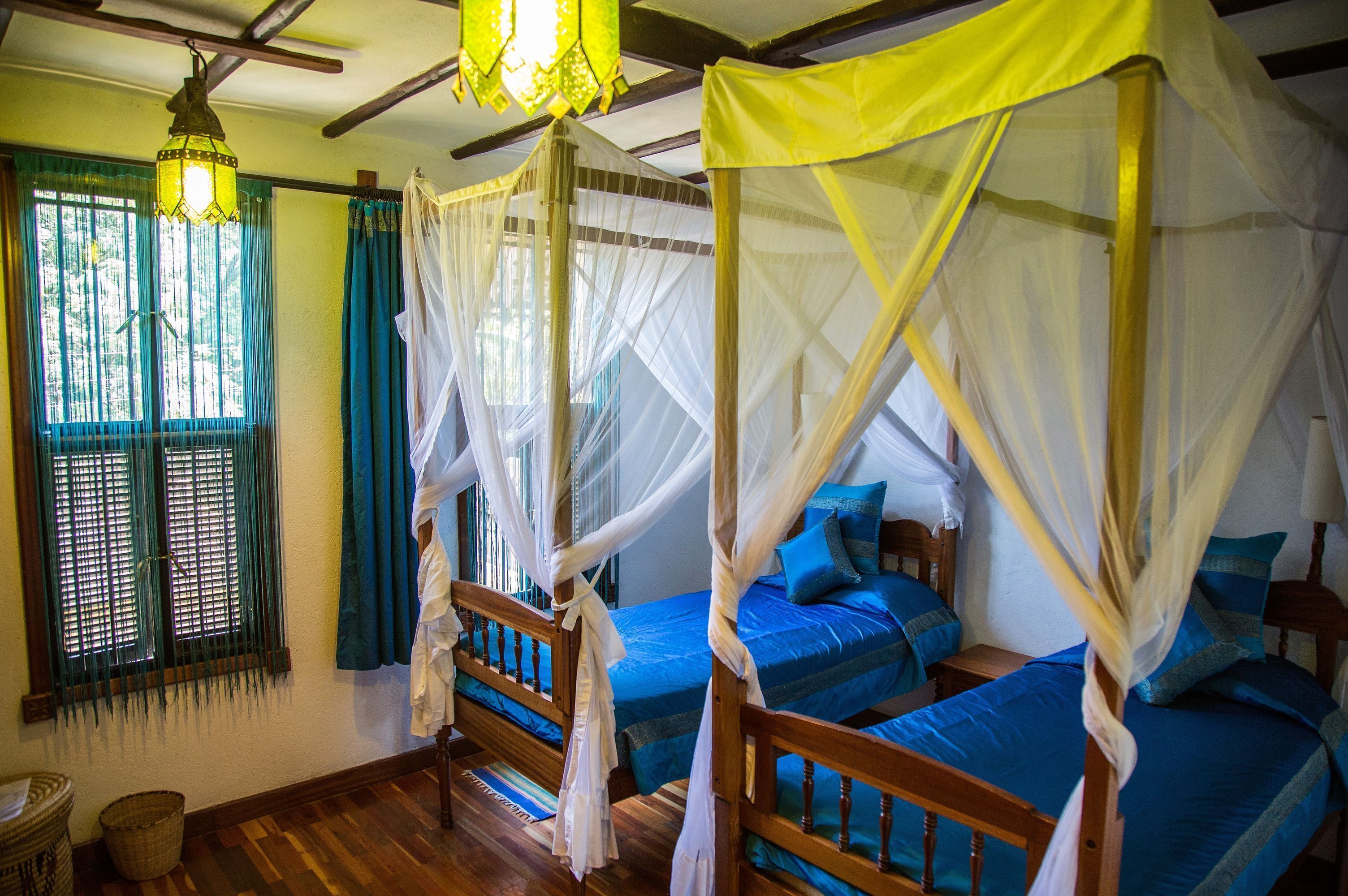 Una habitación con dos camas de madera, cada una con dosel y almohadas azules.