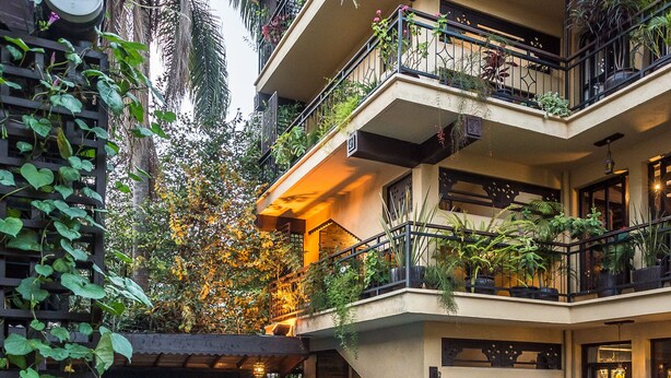A multi-level hotel with a central swimming pool surrounded by lush greenery and potted plants. - The King Post (Nairobi)