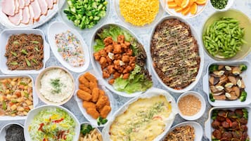 Variedad de platos que incluyen jamón en rodajas, brócoli, maíz y vegetales mixtos.