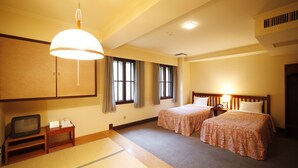 A hotel room with two beds, a television, a small table, and a traditional Japanese tatami mat floor. - Hakuba PAIPU NO KEMURI (Hakuba)