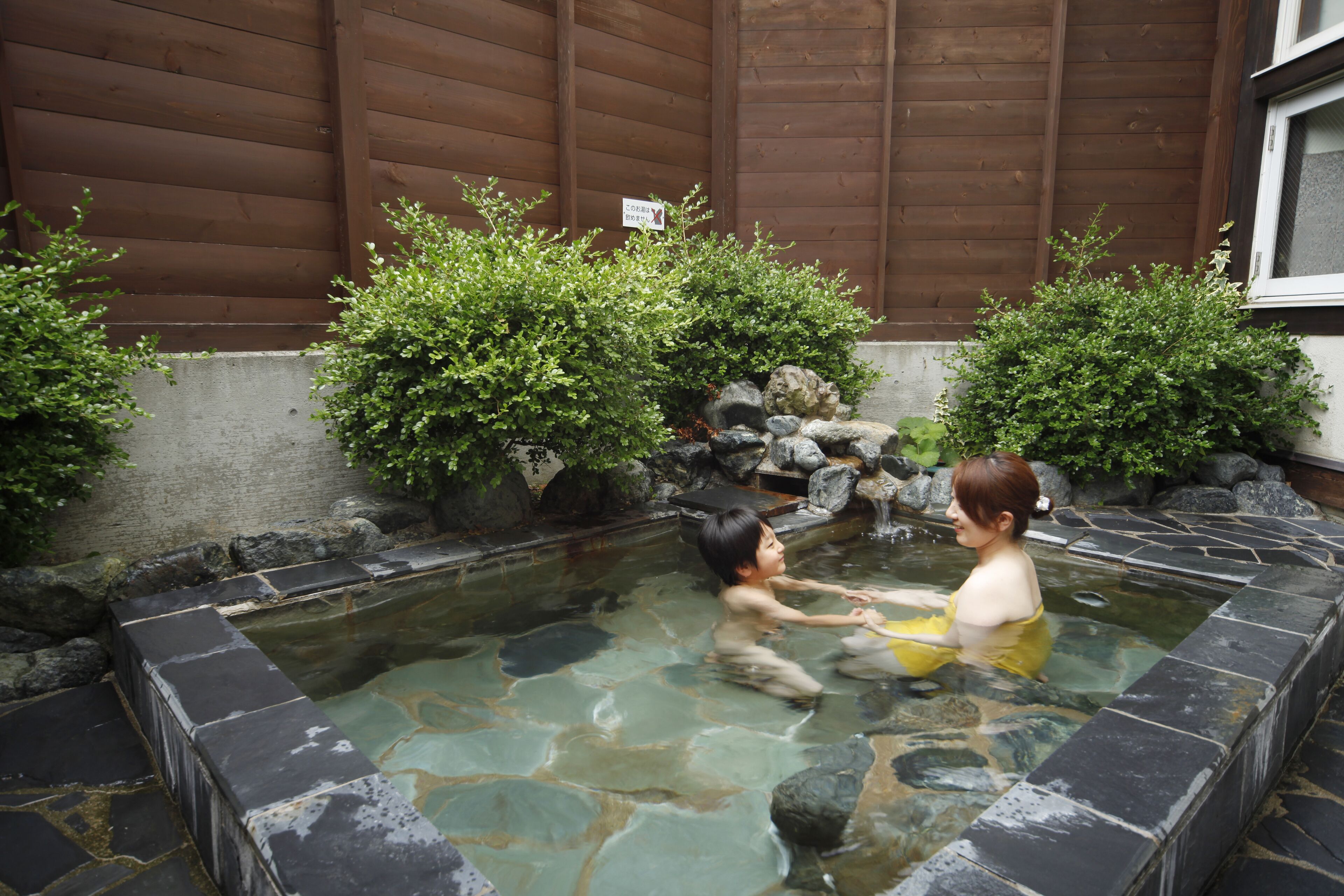 A traditional Japanese onsen with stone walls and a wooden backdrop.