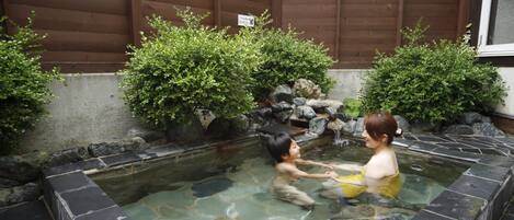 A traditional Japanese onsen with stone walls and a wooden backdrop.