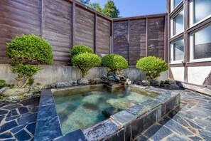 A stone pool with a clear water edge, surrounded by a stone deck and a wooden fence. - Hakuba PAIPU NO KEMURI (Hakuba)