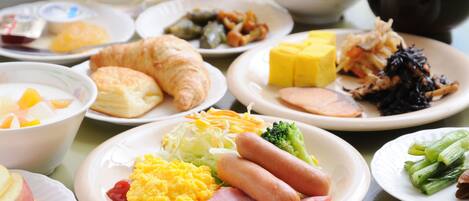 Una mesa de desayuno con distintos platos, como huevos, salchichas y verduras.