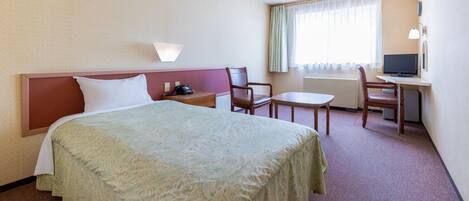A hotel room with a bed, a desk, a chair, and a television.