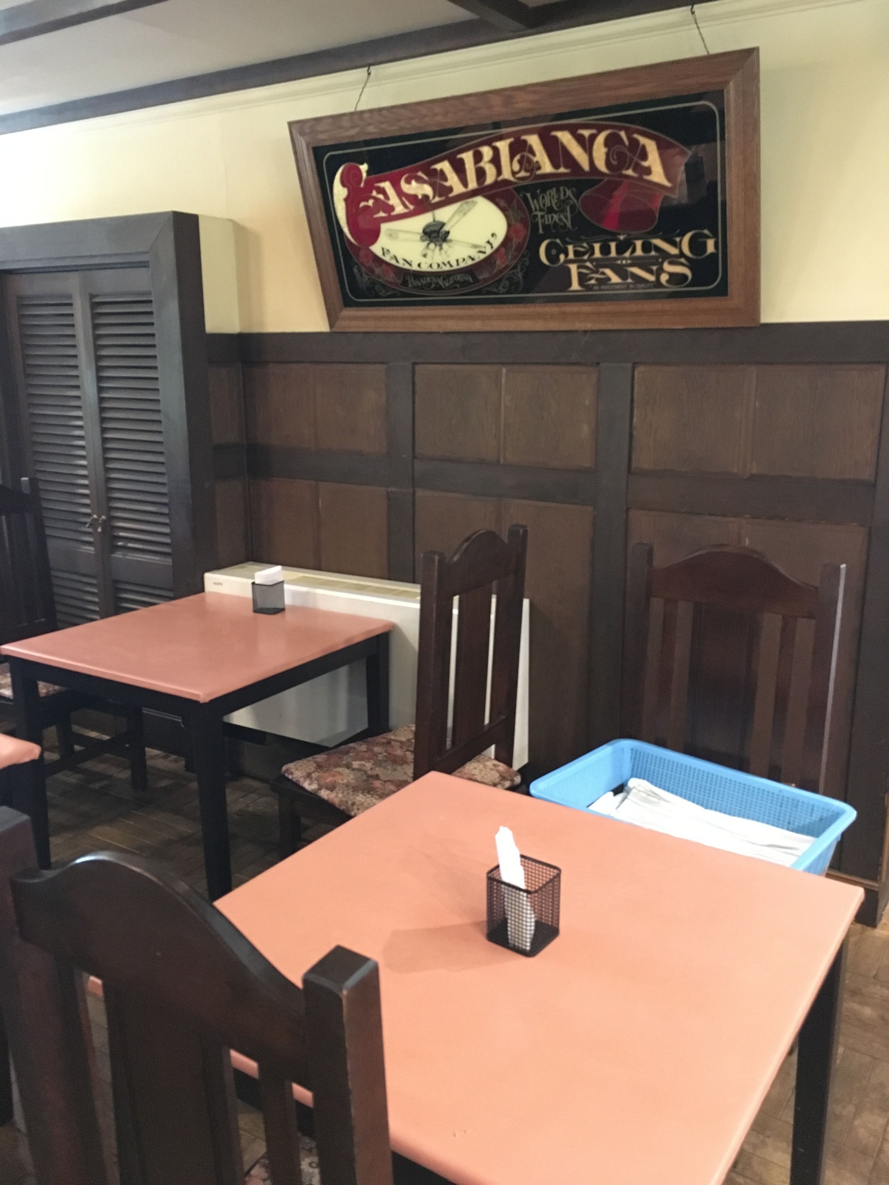 A restaurant interior with wooden paneling, a framed sign above the counter, and a blue basket on the table.