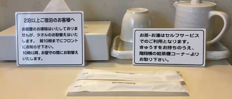 Zona de recepción de un hotel con un letrero, una tetera, una taza de té y una caja de pañuelos.