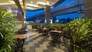 An indoor dining area with checkered flooring, black metal chairs, and potted plants. - Hotel 88 Fatmawati Jakarta by WH (Jakarta)