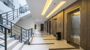 A modern hotel lobby with a staircase, elevators, and a clean, tiled floor. - Hotel 88 Fatmawati Jakarta by WH (Jakarta)