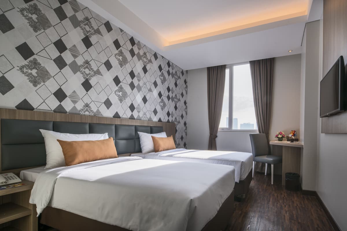 A hotel room with a large bed, a desk, and a TV.