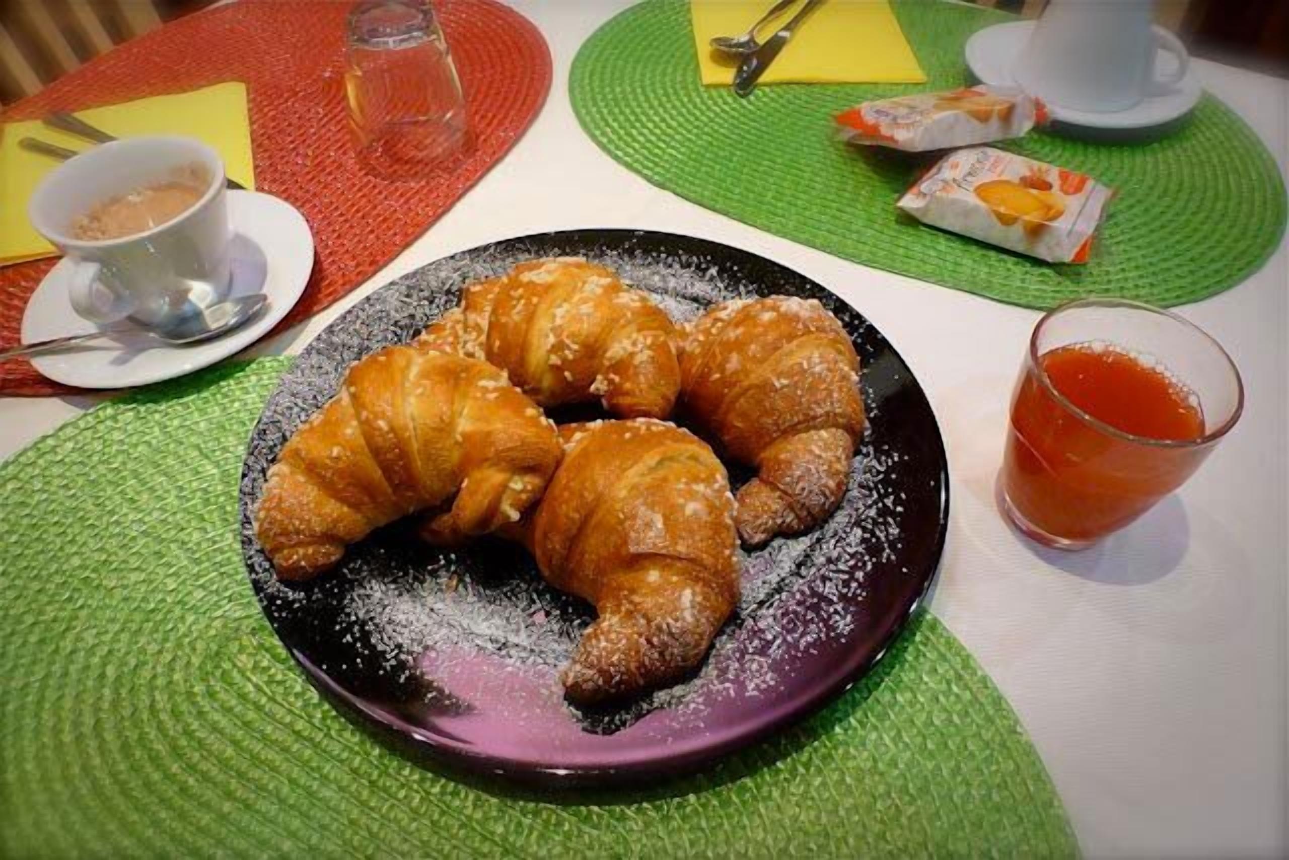 Une assiette de croissants sur une table, avec une tasse de café et un verre de jus de fruits.