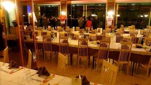 Un restaurant doté de nombreuses tables et chaises, d’un espace buffet et d’une grande fenêtre.