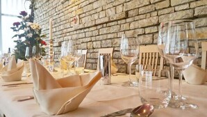 Une table à manger dressée avec des serviettes blanches, des verres à vin et un vase rempli de fleurs.