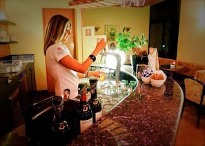 A bar area with a bartender preparing drinks, a countertop with bottles, glasses, and a bowl of snacks. - Hotel Mirella & Ristorante Don Bacco (Orsago)