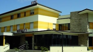 Un hôtel à la façade jaune et blanche, avec une entrée bien visible et un escalier menant à cette entrée.