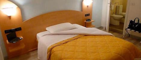 A hotel room with a bed, bedside tables, and a laptop.