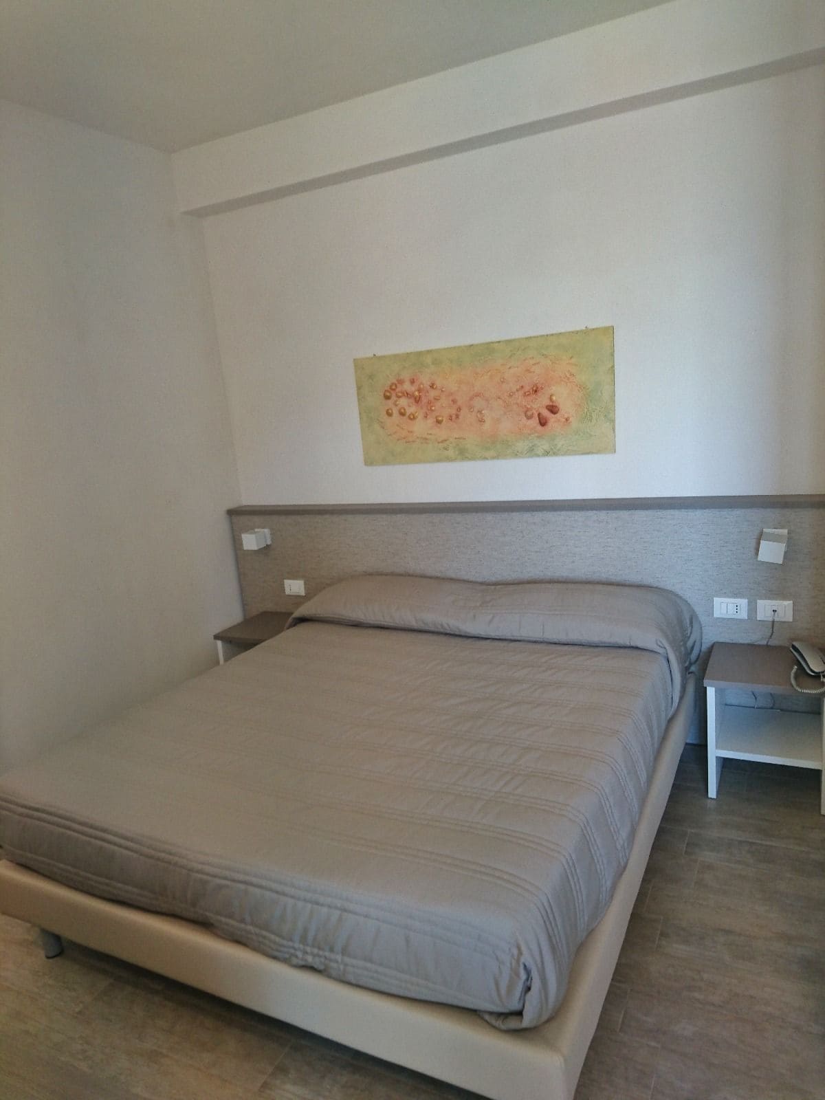 Une chambre à coucher avec un lit, une table de chevet et une œuvre d’art accrochée au mur.