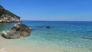 Una playa despejada con formaciones rocosas y aguas tranquilas.