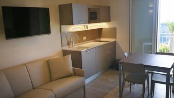 A modern kitchen with a built-in oven, a sink, and a dining area with a table and chairs.