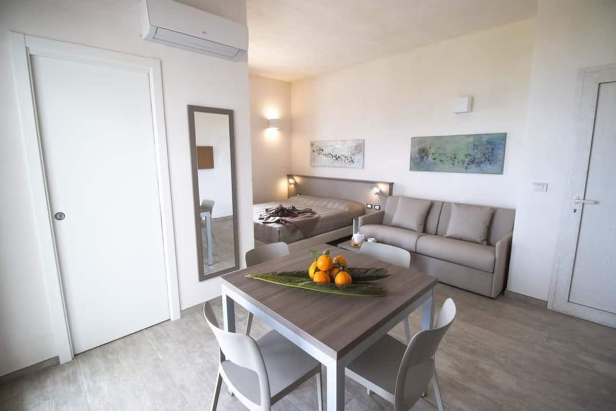 A compact living space with a dining area, a sofa, and a bed.