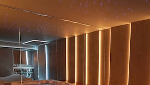 Un cuarto de spa con dos jacuzzis, suelo de madera y un diseño moderno con paneles de luz verticales.