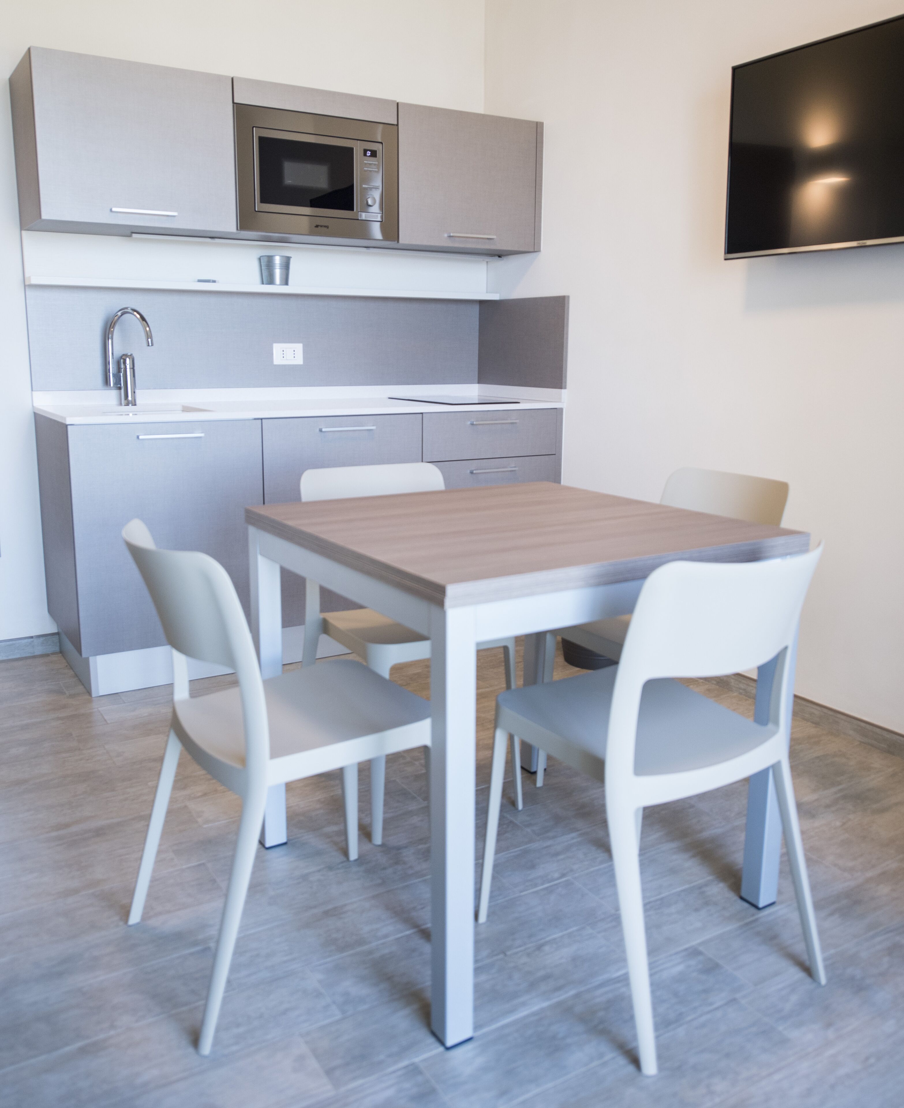 A modern kitchen with a microwave, sink, and cabinets. There is a dining table with four chairs.