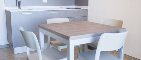 A modern kitchen with a microwave, sink, and cabinets. There is a dining table with four chairs.
