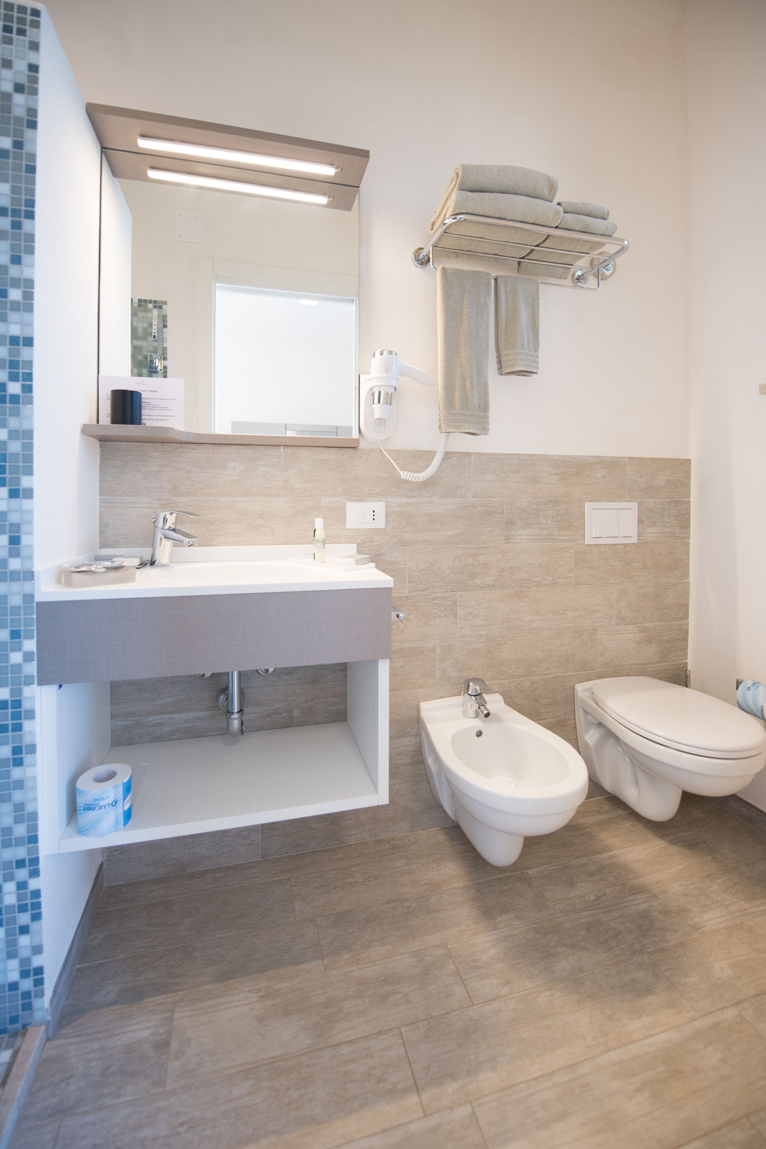 Een moderne badkamer met een witte wastafel, toilet en bidet.