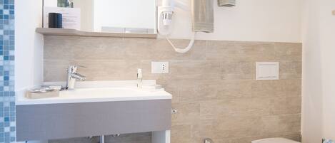 A modern bathroom with a white sink, bidet, and toilet.