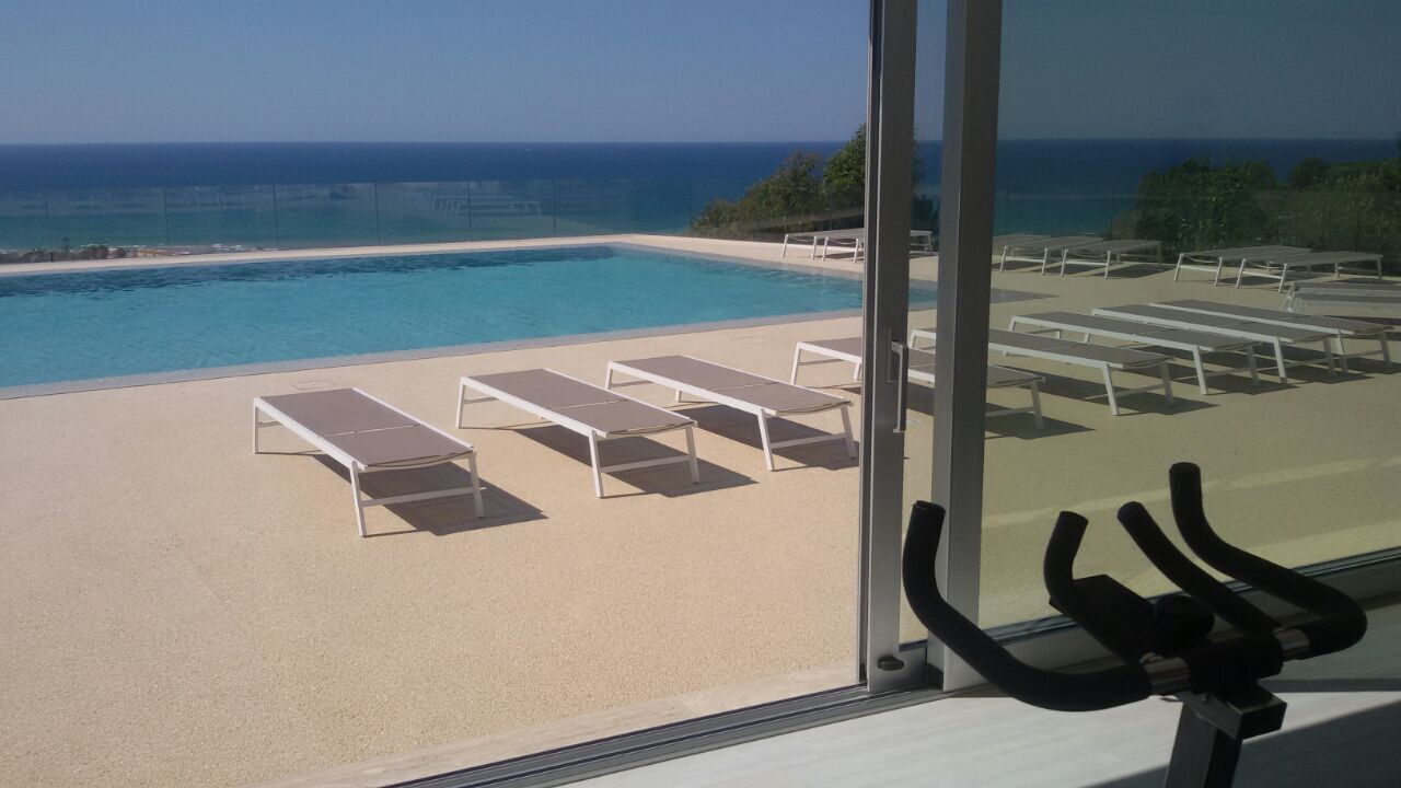 A poolside area with lounge chairs and a view of the ocean.
