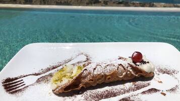 Un dessert servi dans une assiette blanche, avec en arrière-plan une vue panoramique sur une plage.