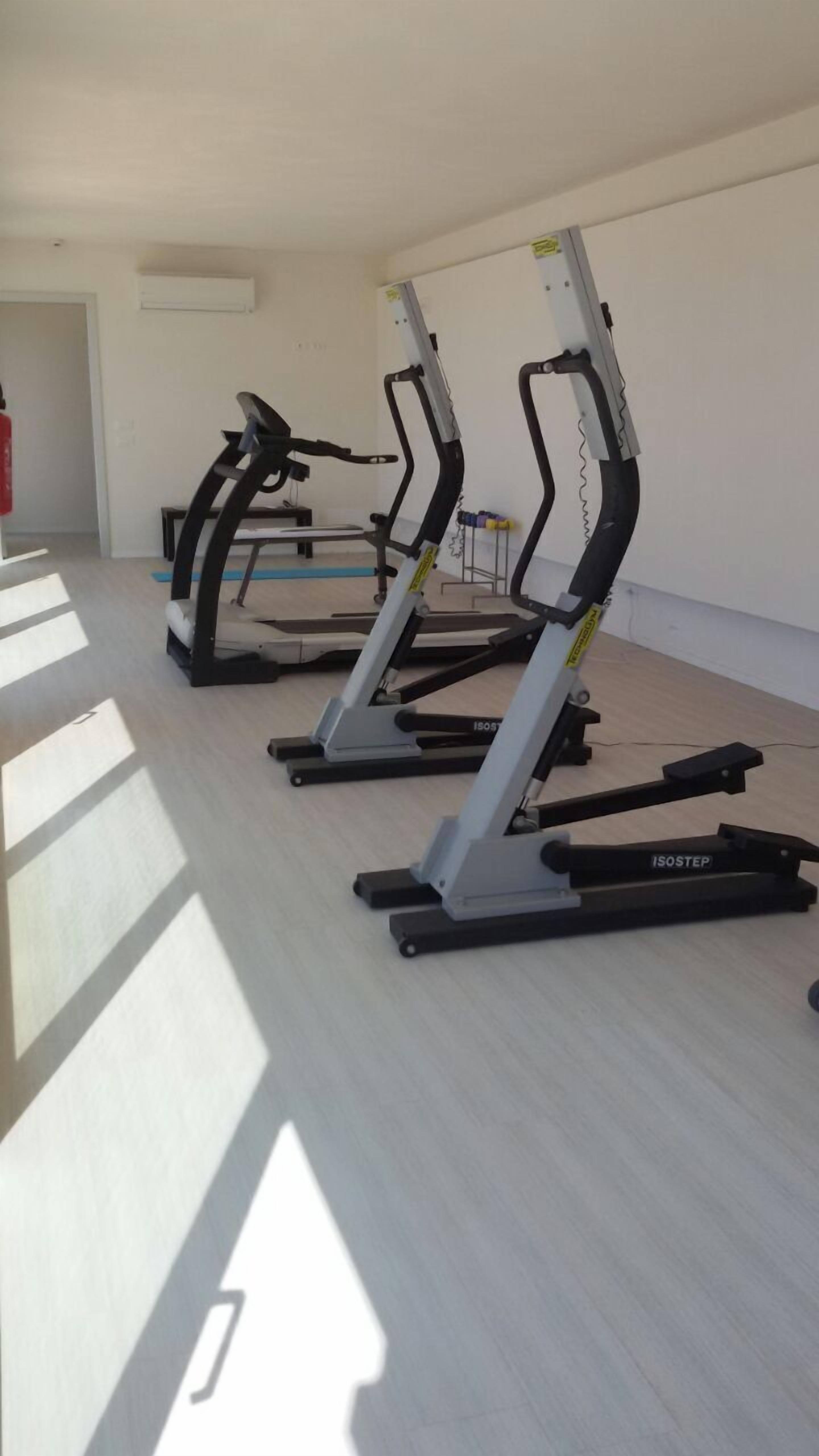 Une salle de sport équipée de tapis de course et d'appareils d'exercice.