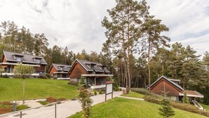 A row of modern houses with sloped roofs, surrounded by a well-maintained lawn and tall trees. - Domaša Zelená Lagúna (Kvakovce)