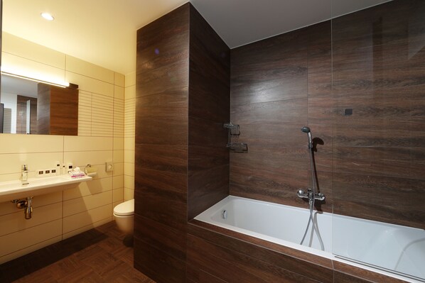 Un baño moderno con lavamanos blanco, inodoro y bañera independiente.