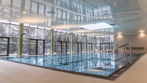 An indoor swimming pool with clear glass walls, multiple lanes, and a diving board. - Domaša Zelená Lagúna (Kvakovce)