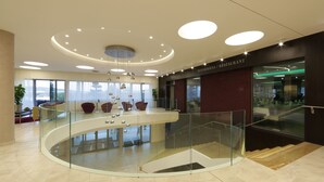 A modern interior with a glass railing, a central seating area, and a staircase leading to an upper level. - Domaša Zelená Lagúna (Kvakovce)