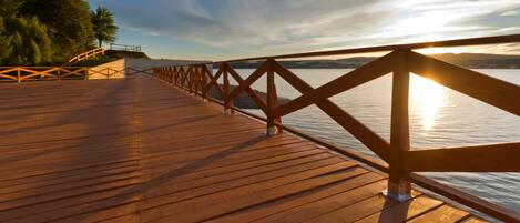 A wooden deck with a railing overlooking a body of water.